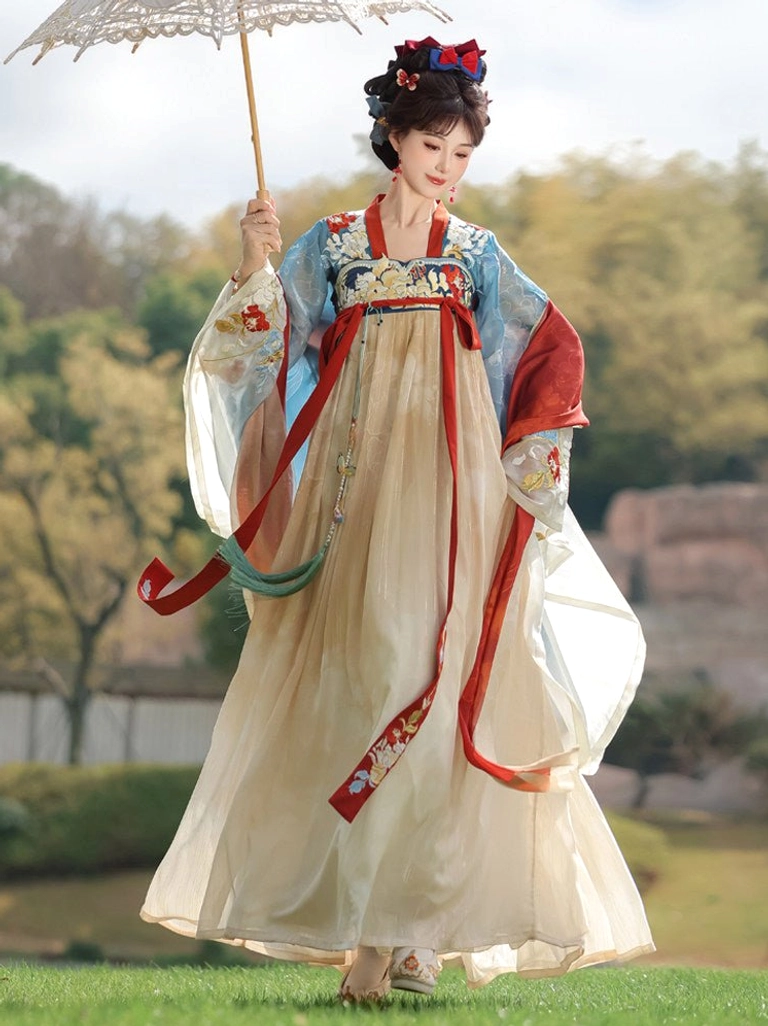 Side full-body walking view of blue and cream Tang Dynasty Hanfu with wide sleeves, red sleeve accents, flowing pleated skirt, and traditional hair accessories