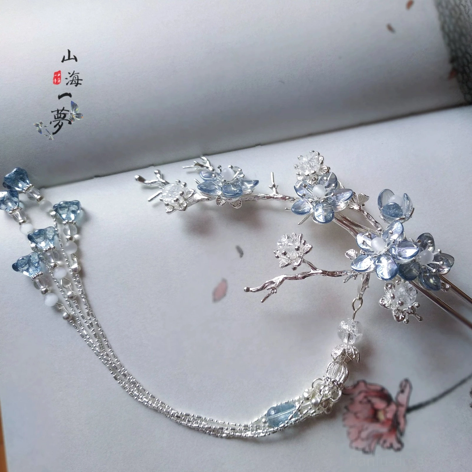 Side angle of a blue crystal Chinese hair ornament with silver-tone branches chain tassel and blue decorative beads