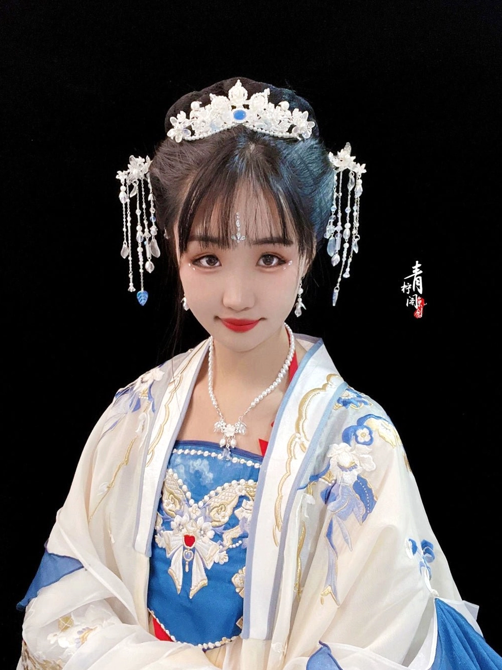 Model wearing blue and white hanfu with blue crystal fairy tiara forehead headpiece matching hairpins and elegant traditional styling