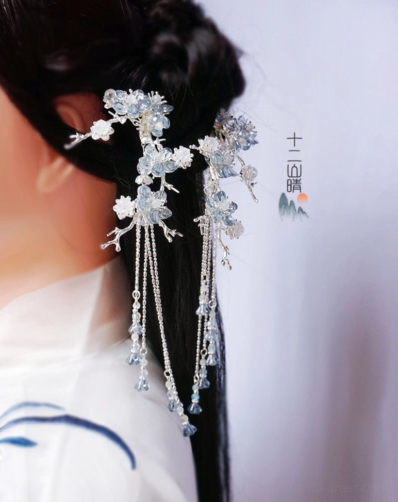 Blue crystal plum blossom hanfu hairpin with silver tassels styled in a traditional Chinese hair bun with white patterned hanfu
