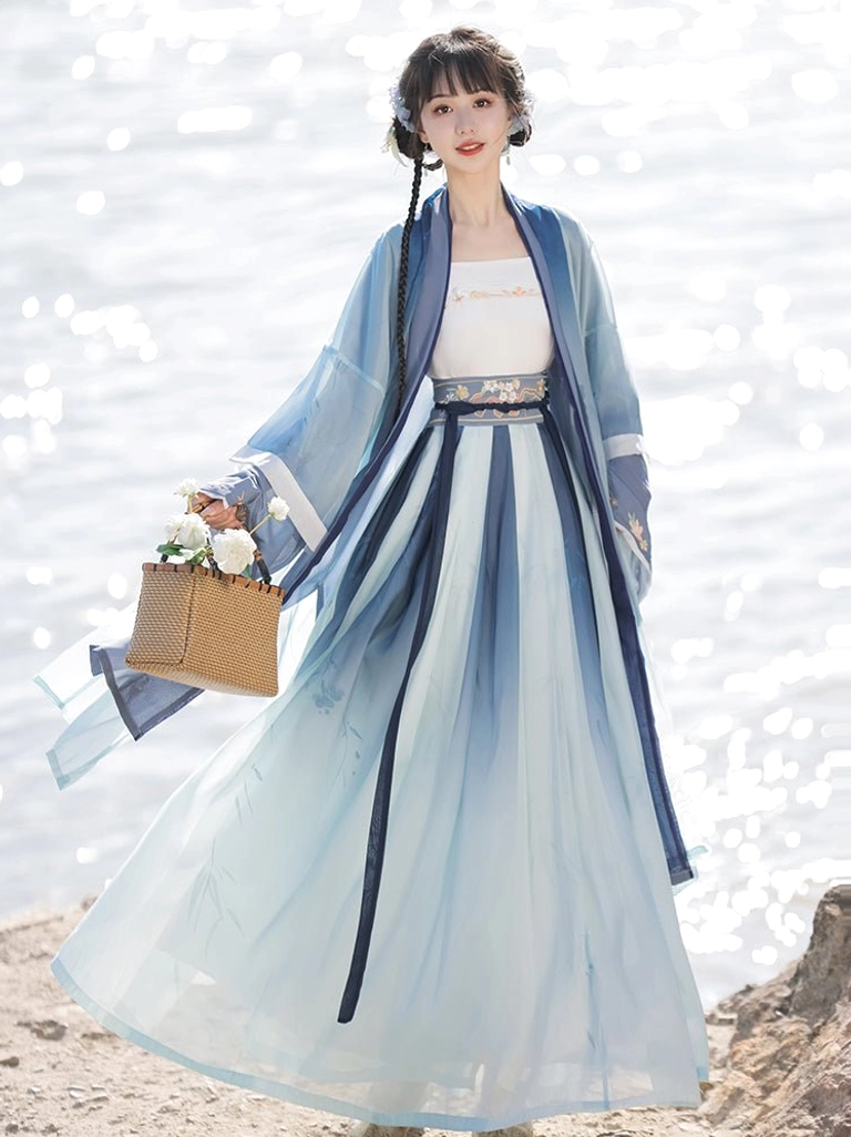 Three-quarter front view of blue to cyan gradient Song Dynasty Qiyao Ruqun Hanfu with dark blue side stripes, matching outer robe, waist sash, and woven floral handbag