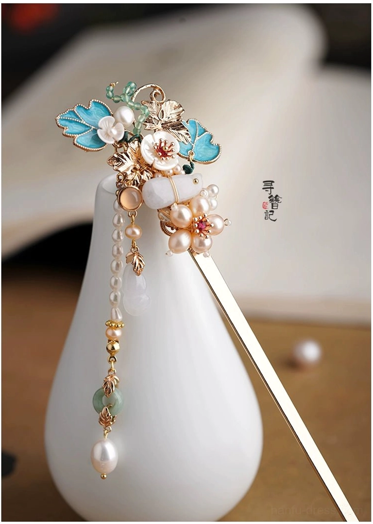 Blue floral Chinese Hanfu hairpin with jade style gourd pendants pearl beads and multi strand tassels on a wooden table