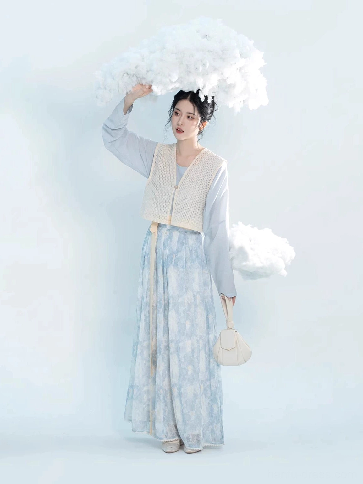 Three quarter view of blue floral Tang Hanfu outfit with watercolor flower print pleated skirt and beige crocheted overlay