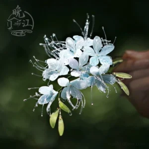 Handmade blue flower Chinese hair stick with translucent gradient petals green leaves and water drop decorations shown against a soft natural background