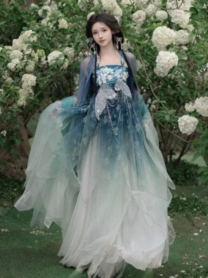 Full body front view of blue gradient Tang Dynasty style Heziqun Hanfu dress with floral embroidered bodice, sheer big sleeve cardigan, flowing layered skirt, and traditional Chinese hair accessories in a garden