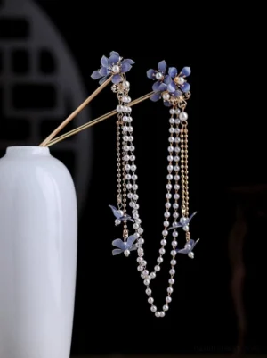 Blue hydrangea Chinese hair pin with pearl center, gold hair shaft, layered tassels, and butterfly pendant displayed on porcelain