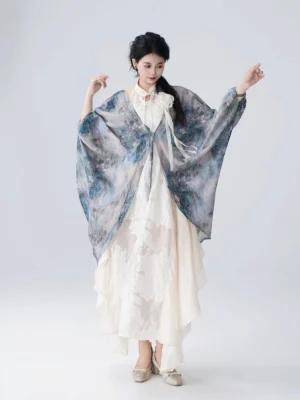 Full-body front view of a woman wearing a blue ink-wash modern Hanfu butterfly cardigan over an off-white Chinese-style dress with flowing batwing sleeves