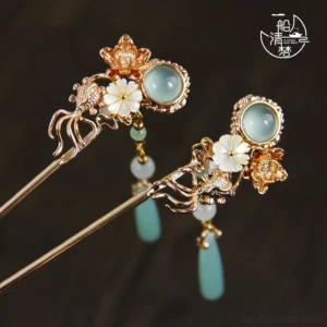 Blue jade style floral Chinese hair sticks with white shell petals, rose gold tone metal frames, and teardrop pendants on dark wood