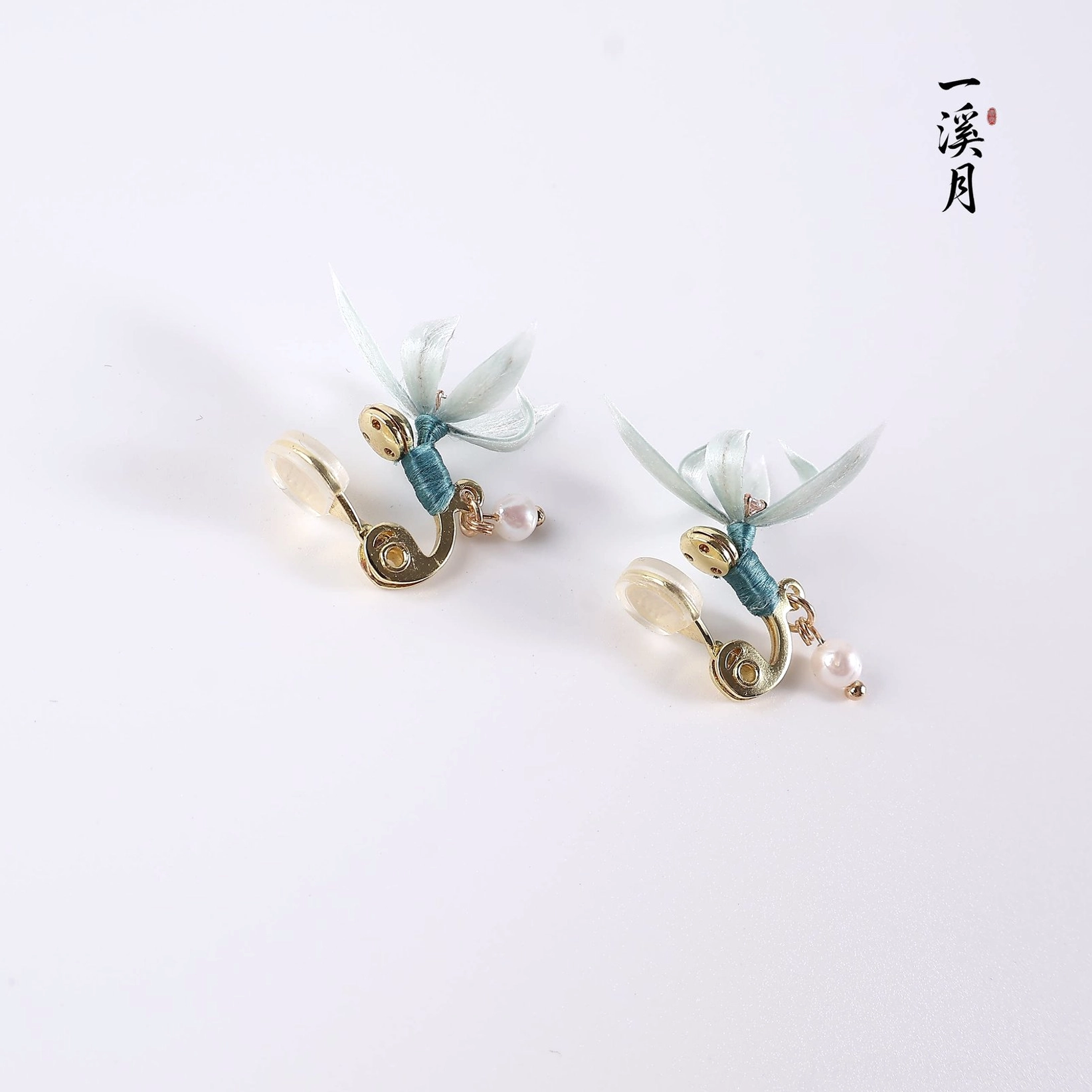 Comfort clip-on blue orchid pearl drop earrings for non-pierced ears with teal wrapped gold tone ear clips on a neutral background
