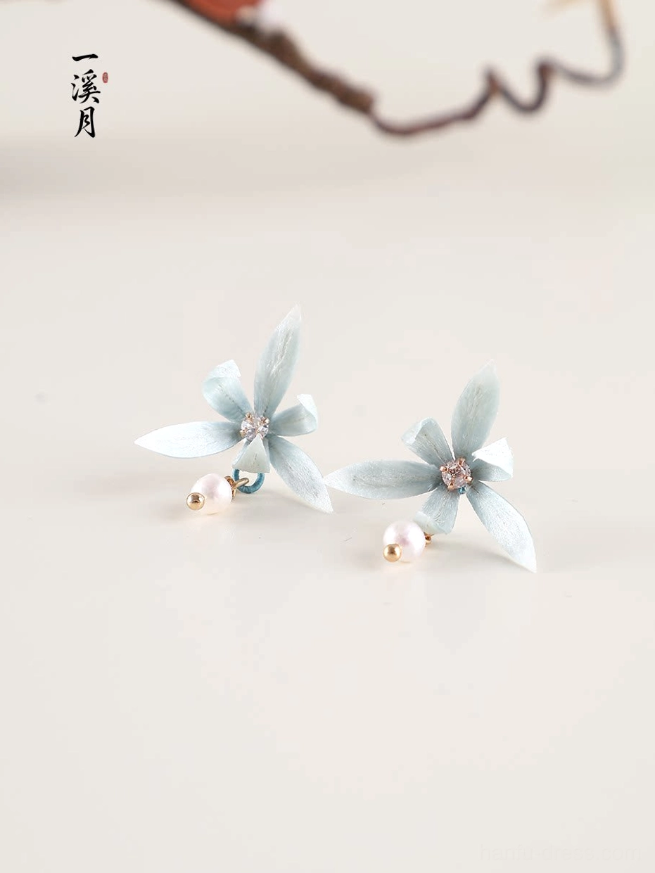 Blue orchid Hanfu earrings with pearl dangles and gold tone details displayed on a light beige background with dried branch accent