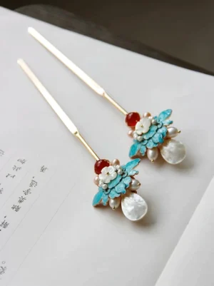 Pair of vintage-inspired blue peony Chinese hair sticks with gold-tone shafts, white shell flowers, freshwater pearls, and red agate ornaments displayed on traditional calligraphy paper