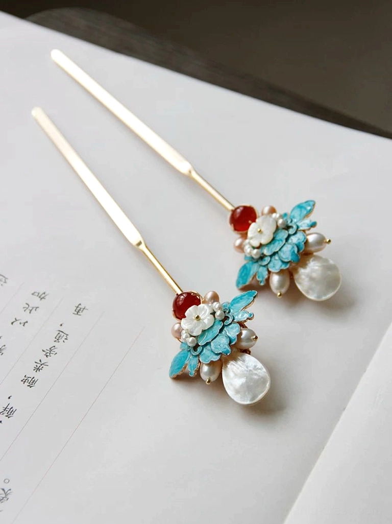 Pair of vintage-inspired blue peony Chinese hair sticks with gold-tone shafts, white shell flowers, freshwater pearls, and red agate ornaments displayed on traditional calligraphy paper