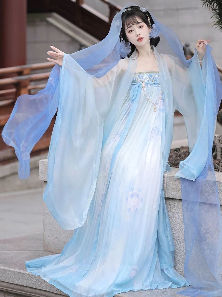 Blue Tang Dynasty Qixiong Ruqun Hanfu with attached sheer shawl, waist ornaments, and wind-blown sleeves beside traditional Chinese architecture