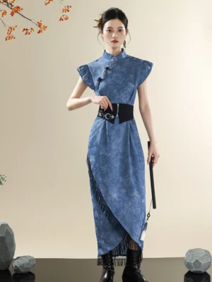 Front full-body view of a blue tie-dye modern Hanfu qipao dress with Mandarin collar, frog buttons, ruffled cap sleeves, asymmetrical fringe hem, black wide waist girdle, and folding fan