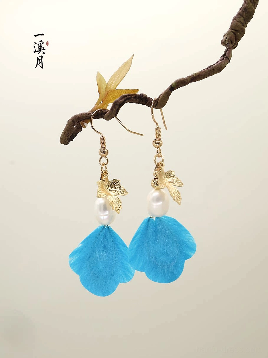 Blue velvet flower Chinese drop earrings with gold maple leaf charms and pearl-like bead accents displayed on a natural branch