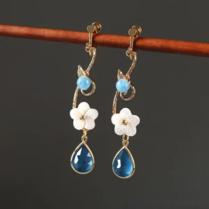 Blue water lily drop Chinese earrings with comfort clip-on backs, white flower charms, pale blue beads, gold tone vine links and dark blue teardrop pendants