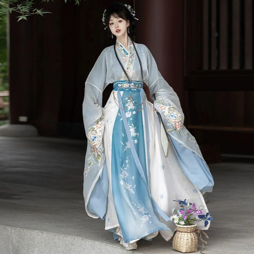 Blue and white gradient Wei Jin Dynasty Qiyao Ruqun Hanfu side view showing floral skirt embroidery, flowing wide sleeves, blue waist belt, and layered cross-collar styling