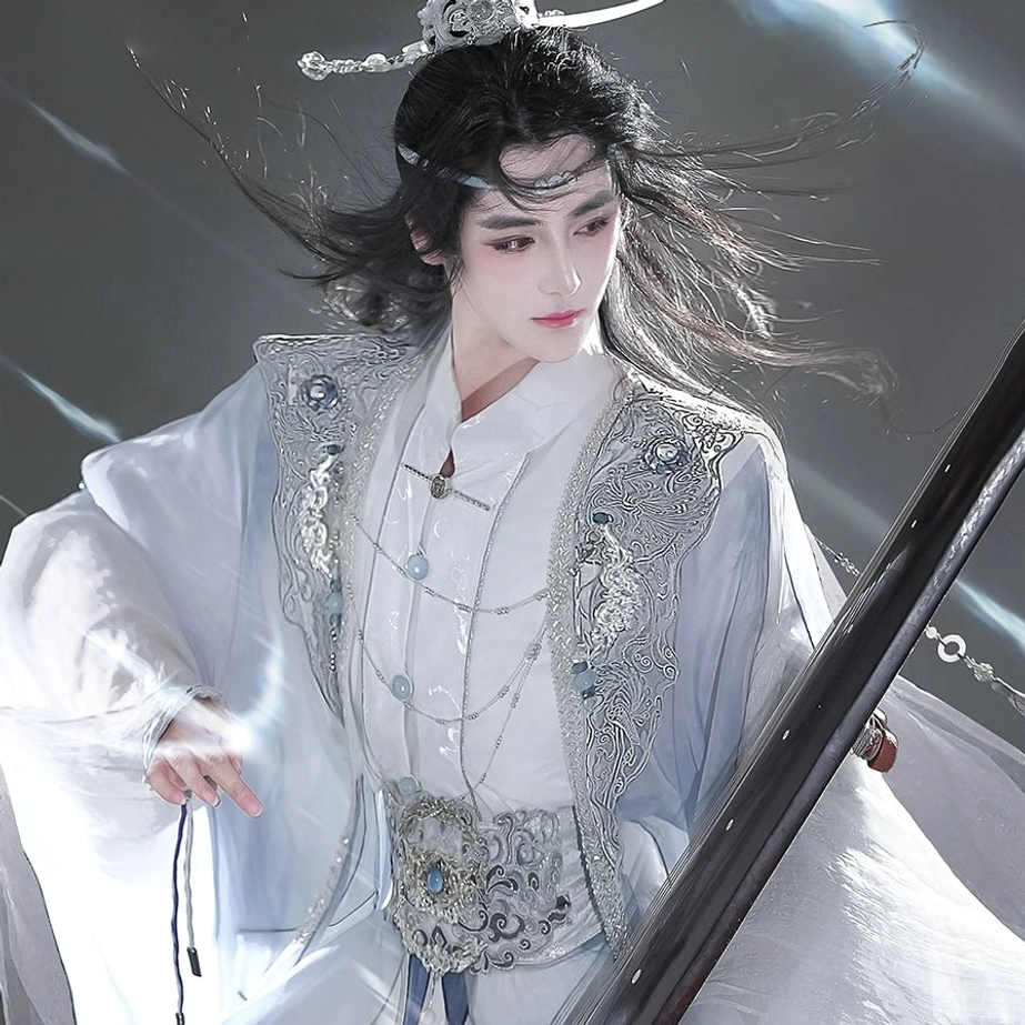 Close-up front view of a blue and white unisex Hanfu costume featuring silver floral embroidery, layered necklaces, a traditional hair crown, and an ornate waist ornament with blue accents