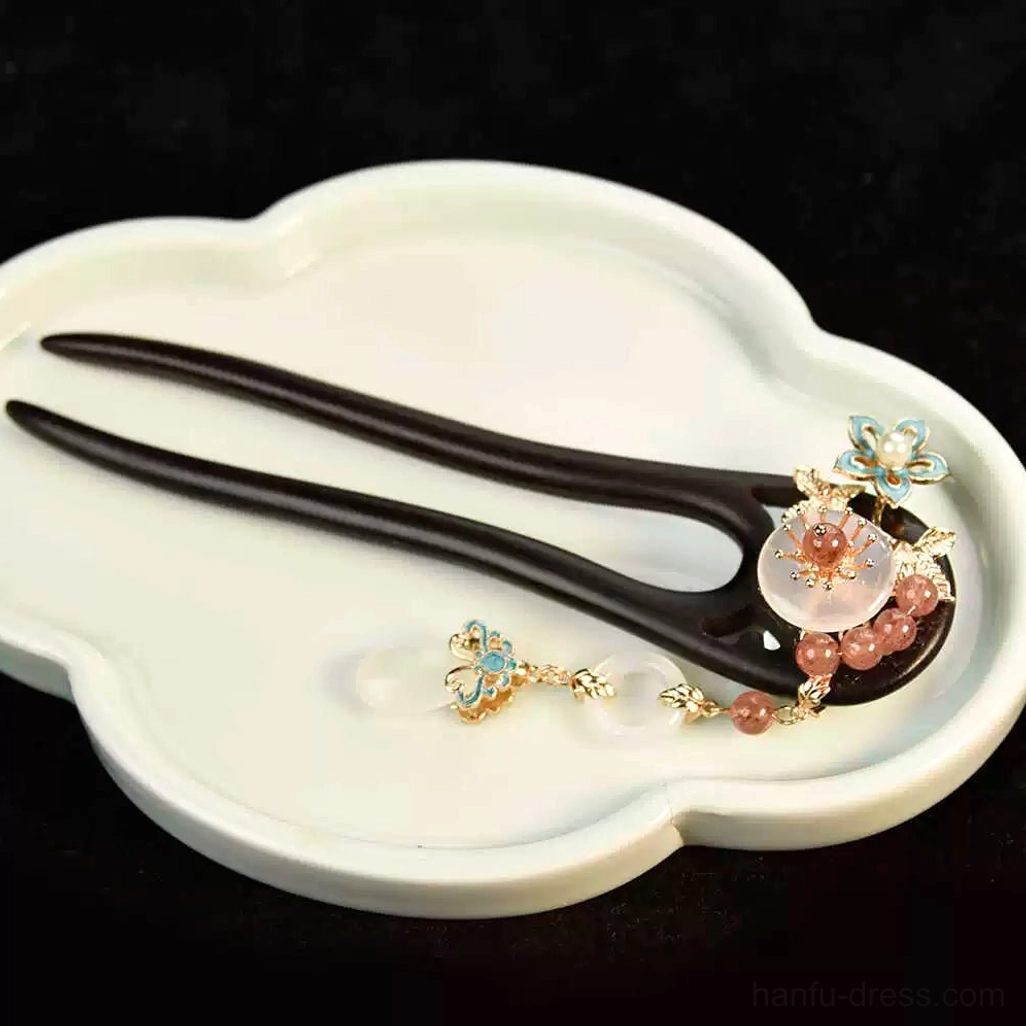 Full flat lay of blush floral double-pronged Chinese hair stick with long tassel chains on white cloud-shaped tray