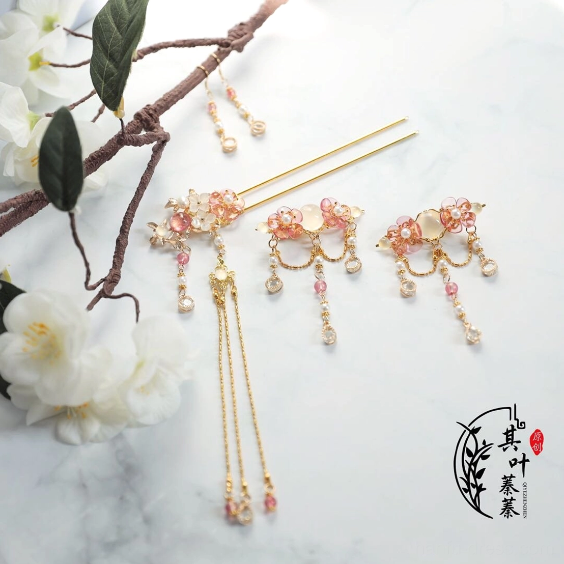 Complete blush pink floral Hanfu hair accessory set with gold tone hairpin, matching side clips, white stone style accents and long chain tassels on a marble background