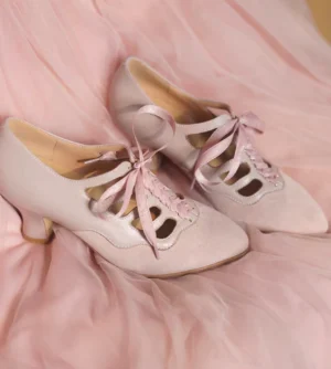 Blush pink vintage Qipao Mary Jane heels with pointed toes, ribbon laces, cutout vamp, mixed suede and smooth upper, and low block heels displayed on pink tulle