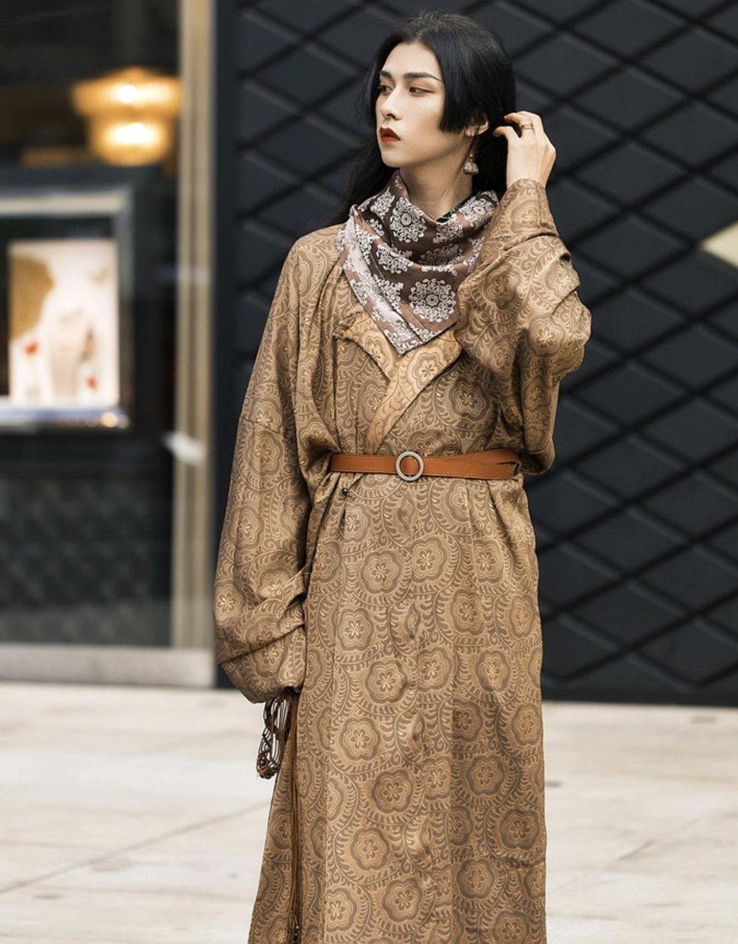 Front three quarter view of a brown Tang Dynasty Hanfu robe with textured jacquard cross collar design leather belt printed scarf and hanging hem accessory