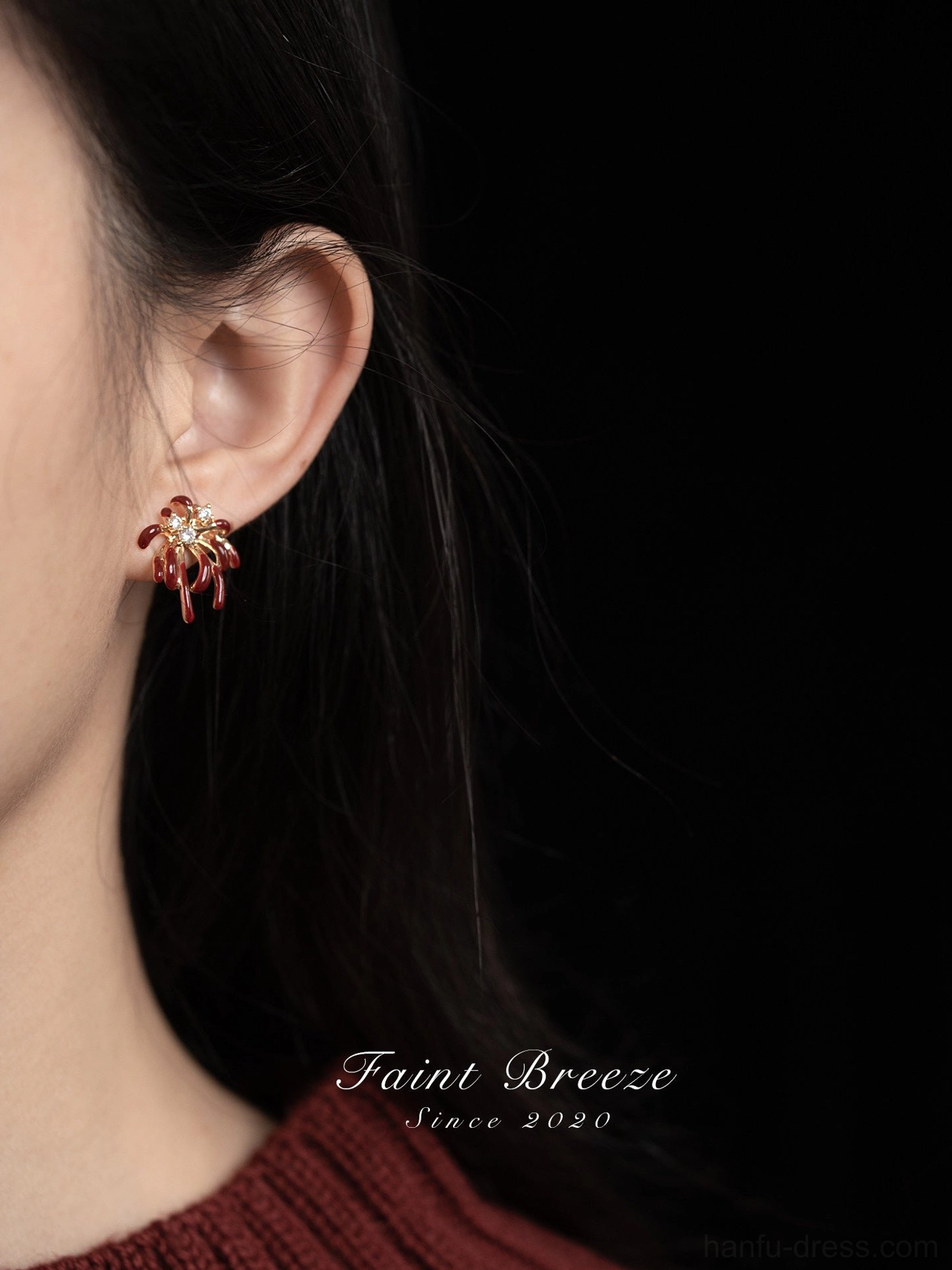 Close-up of burgundy firework stud earring worn on ear, gold-tone Chinese festival jewelry with crystal accent