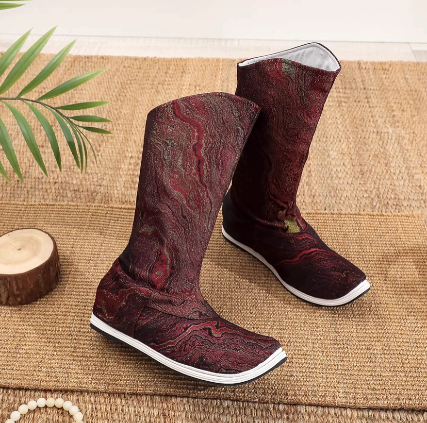 Three-quarter side view of burgundy high-top Chinese Hanfu boots showing the white inner lining, textured fabric, white midsole, and black anti-slip outsole