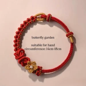Butterfly Garden red handwoven Chinese knot bracelet with golden flower charm and traditional red knot accents on a light pink background