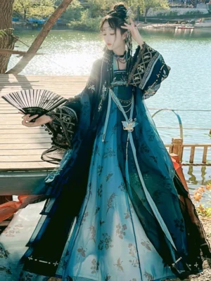Teal and black gradient Tang Dynasty Hanfu Qixiong Ruqun complete set with floral and butterfly skirt motifs, embroidered cuffs, layered waist decorations, and folding fan by a lake