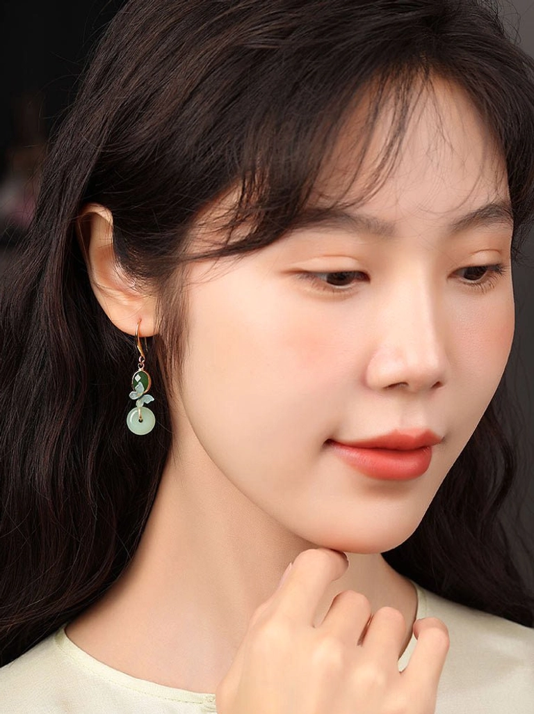 Close-up profile of a model wearing elegant butterfly jade drop earrings with enamel butterfly charms and light green pendants
