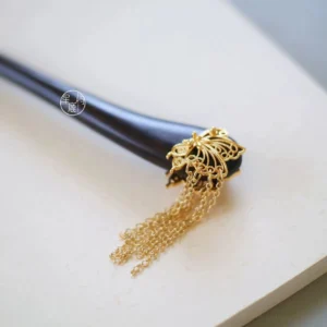 Butterfly tassel Chinese hair stick with a smooth black wood shaft, openwork gold-colored butterfly ornament, and long layered chain tassels on a white background
