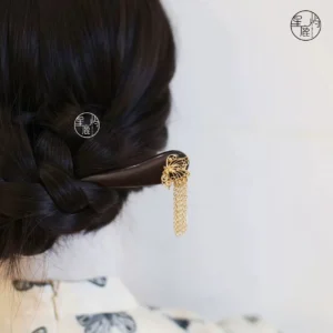 Traditional Chinese butterfly tassel hair stick worn in a braided updo with the delicate gold-colored tassels hanging beside a qipao hairstyle