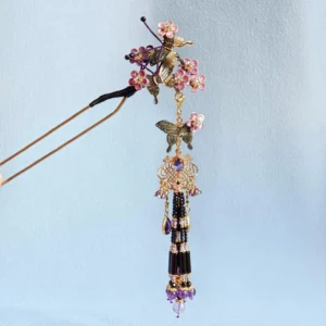 Butterfly tassel Chinese hair stick with pink purple flowers, golden metal butterfly accents, and a long black purple hanging tassel on a light blue background