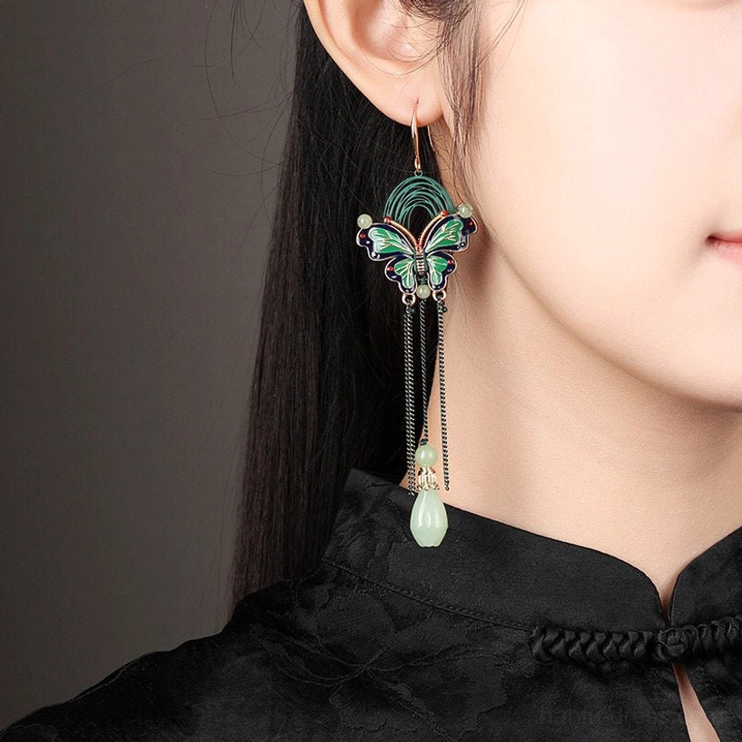 Model wearing butterfly teardrop Chinese earrings with black tassels and green jade style pendants alongside a traditional black Cheongsam