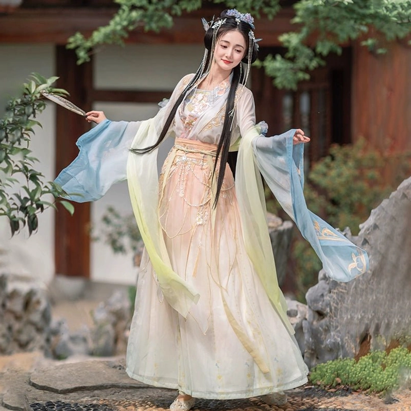 Three-quarter side view of blue-green Calm Waters Qiyao Ruqun Hanfu during a graceful movement pose, highlighting the flowing sleeves, floral embroidery, and layered skirt