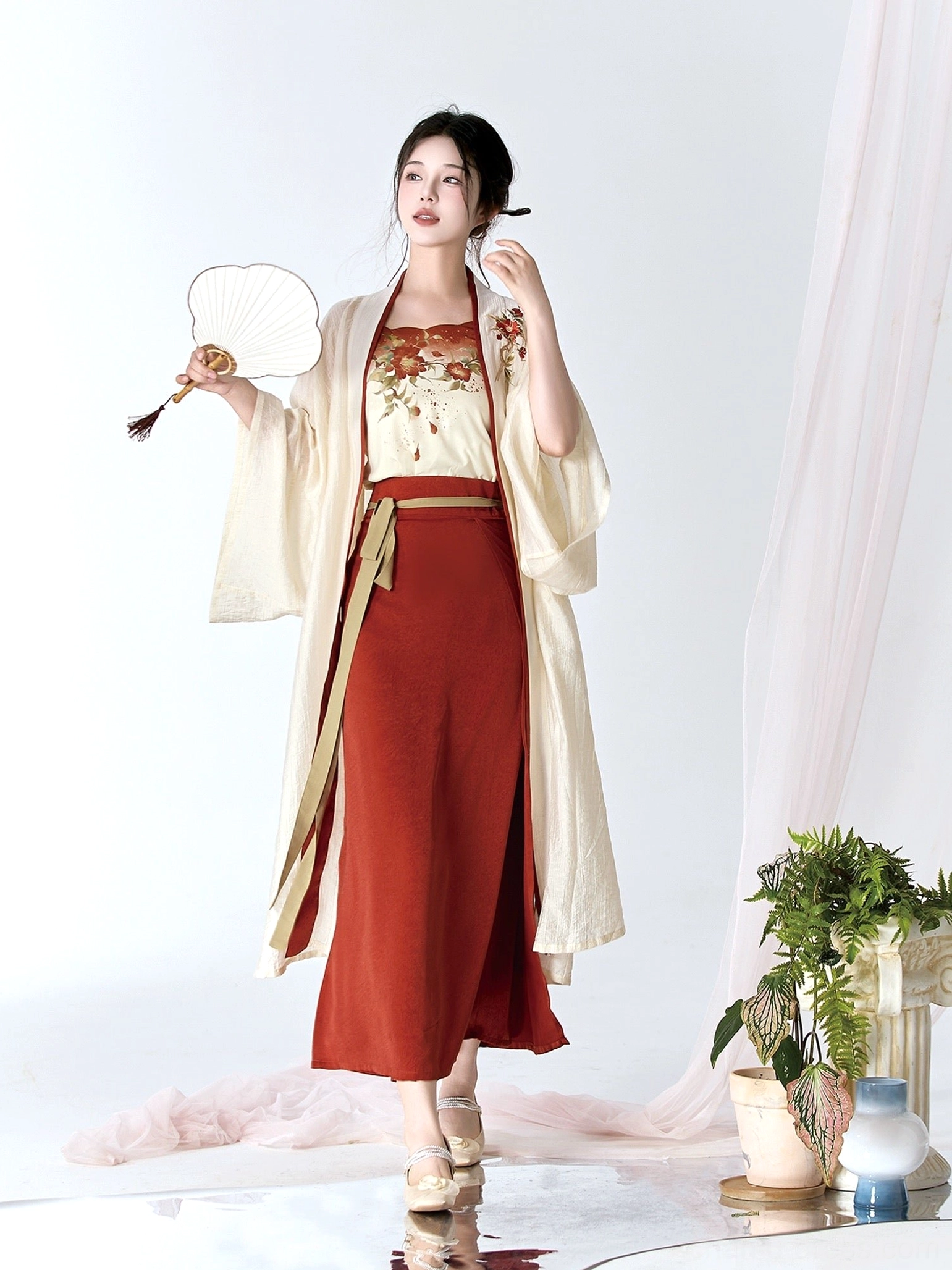Front view of a camellia Hanfu set styled with traditional Chinese coiled hairstyle, floral fans, cream robe, and burgundy skirt
