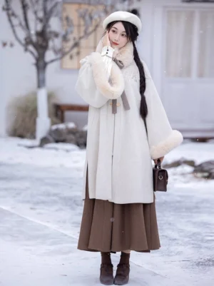 Cappuccino toned winter Ming hanfu outfit with faux fur collar cuffs toggle coat and brown ankle boots styled in a snowy outdoor setting