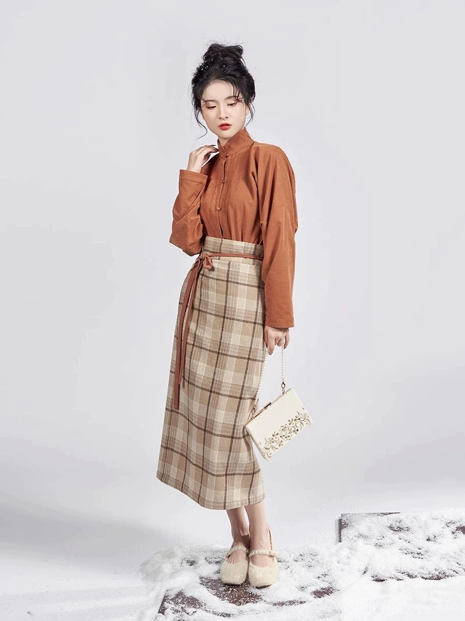 Side view of a caramel brown Hanfu inner top and high-waisted beige plaid mamianqun skirt with waist ties styled with an embroidered handbag