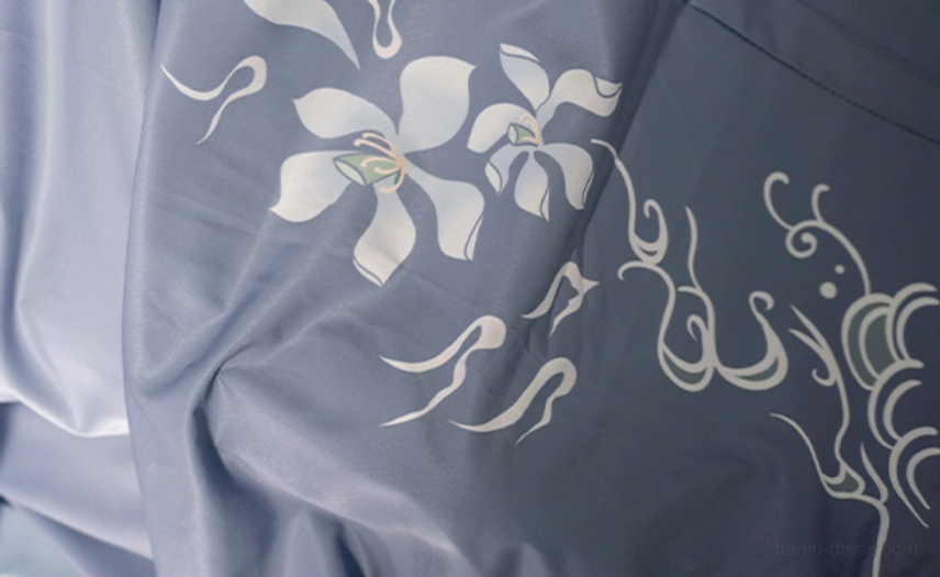 Close up of grey blue Qiyao ruqun fabric with white orchid blossoms and swirling cloud embroidery on Wei Jin style hanfu for men