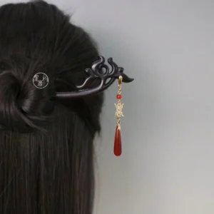 Carved Chinese hair stick with red agate beads, gold charm, and dangling tassel worn in a traditional updo for Hanfu styling