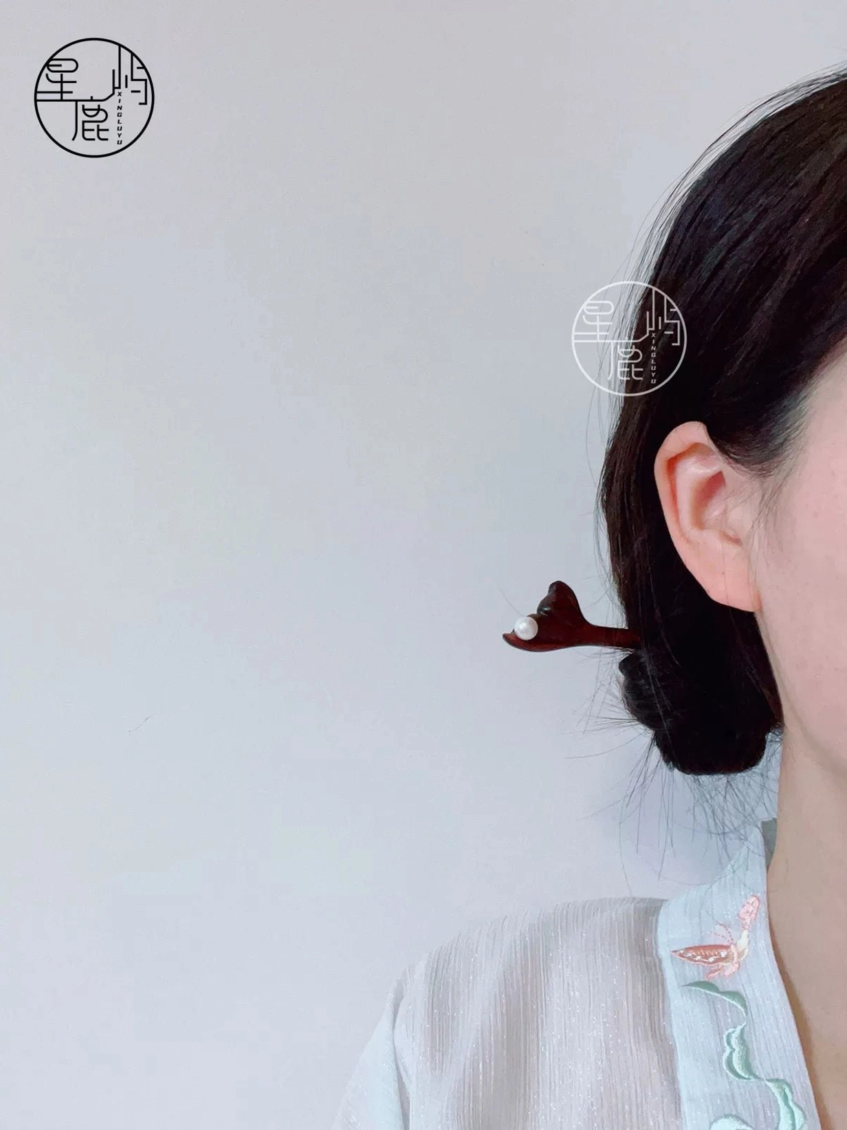 Female model wearing carved flower pearl Chinese hair stick with a light embroidered Hanfu-inspired outfit