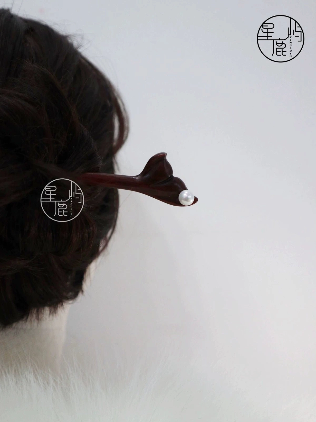 Back view of dark updo styled with a carved flower pearl wooden Chinese hair stick for Hanfu