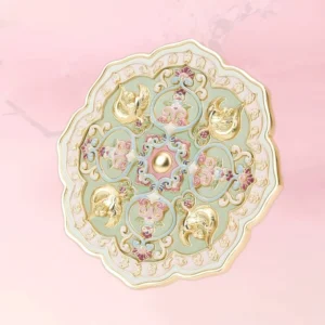 Celadon floral bird Chinese pocket mirror with scalloped gold-toned trim, colorful enamel-style blossoms, and central pearl-like accent on pink background