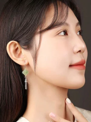 Woman wearing celadon four-leaf clover tassel cheongsam earrings showing elegant long drop earring profile