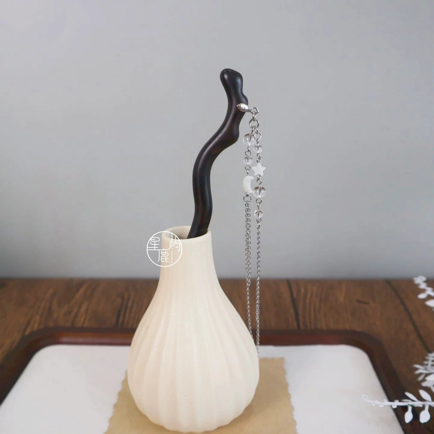 Celestial ebony Chinese hair stick with silver tone moon and star tassel displayed in a ceramic vase