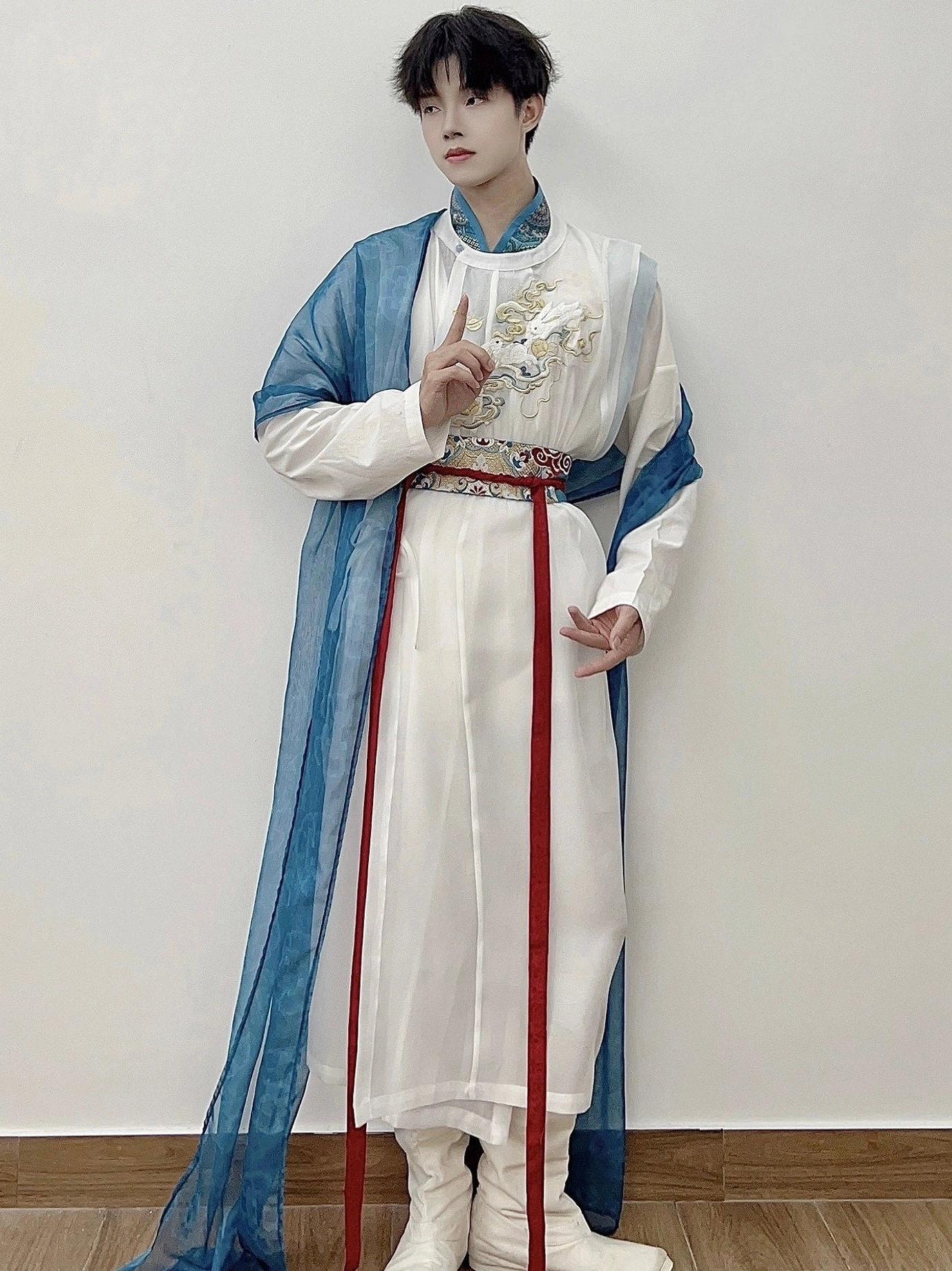 Male model wearing celestial God of War hanfu for men with white robe long blue drapery red sash and dragon chest embroidery