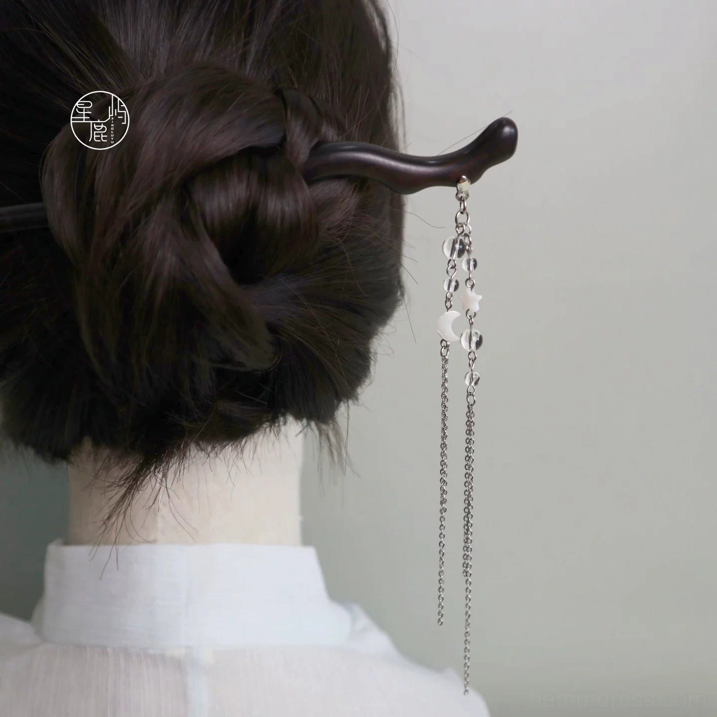 Traditional Chinese hair stick worn in a low bun with moon star tassel hanging elegantly at the back of the neck