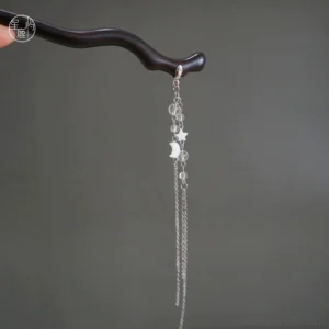 Celestial moon and star ebony Chinese hair stick with long silver tone chain tassel shown against a gray background