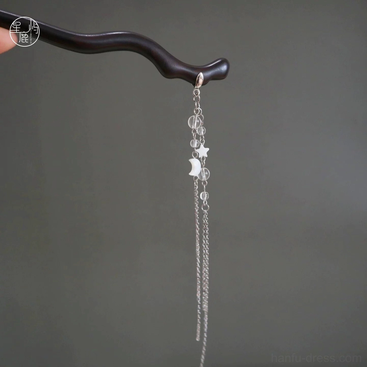Celestial moon and star ebony Chinese hair stick with long silver tone chain tassel shown against a gray background